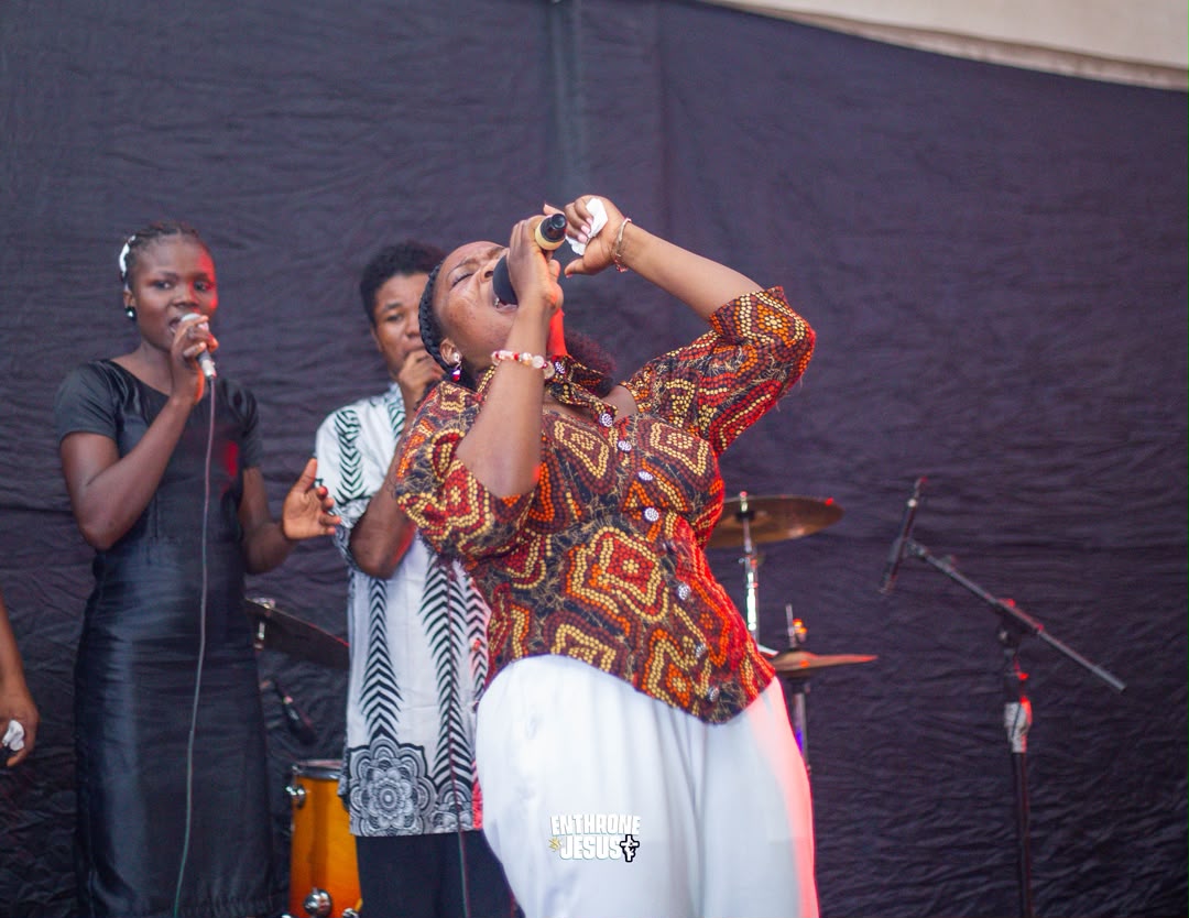 Minister Vida singing with her head thrown back under red stage light at Enthrone Jesus.