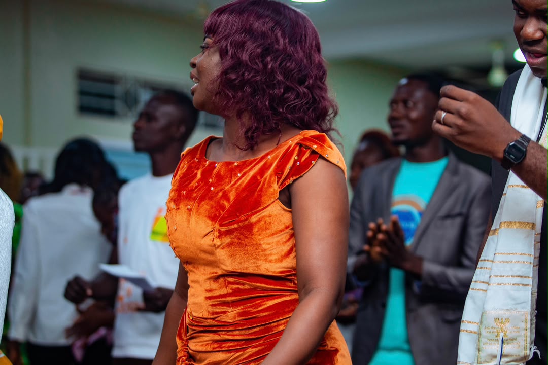 Minister Vida walking among a standing, clapping congregation at Mid-Year Worship 2024.